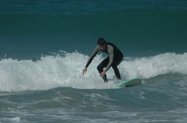 joven cogiendo una ola mientras surfea